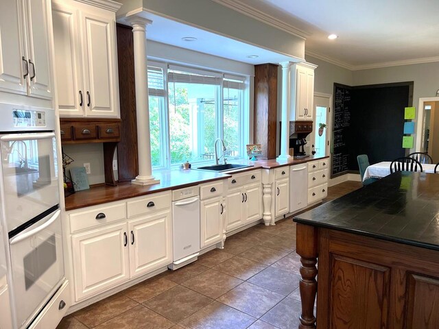 kitchen featuring double oven, dark countertops, and ornate columns