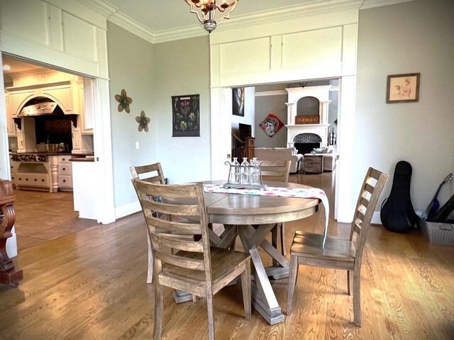 dining space featuring baseboards, a fireplace, ornamental molding, and wood finished floors