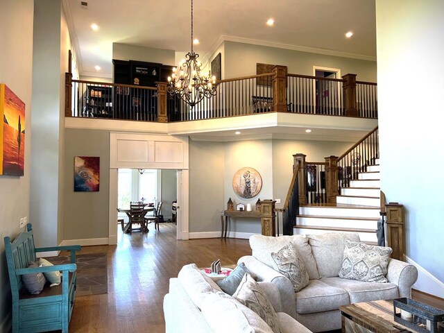 living area with crown molding, a notable chandelier, a towering ceiling, and wood finished floors