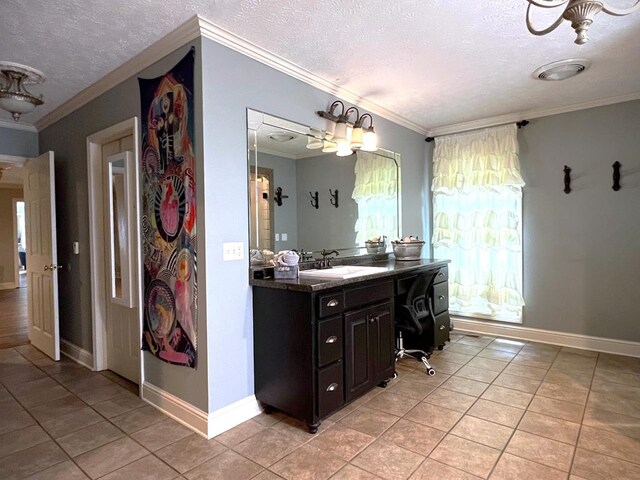 bathroom featuring a textured ceiling, tile patterned flooring, vanity, baseboards, and ornamental molding