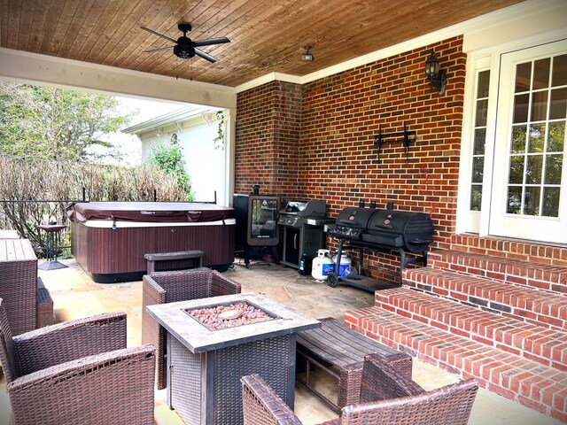 view of patio with an outdoor fire pit, grilling area, a ceiling fan, and a hot tub