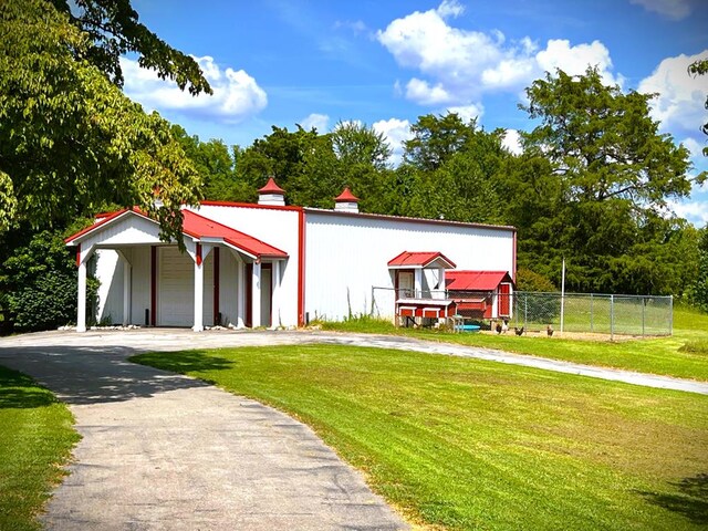 view of front facade with driveway, a front yard, and fence