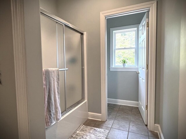 bathroom with tile patterned flooring, shower / bath combination with glass door, and baseboards