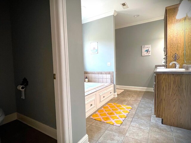 bathroom featuring a bath, baseboards, visible vents, and crown molding