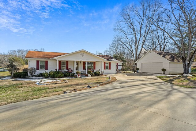 ranch-style home featuring covered porch, a front lawn, and a detached garage