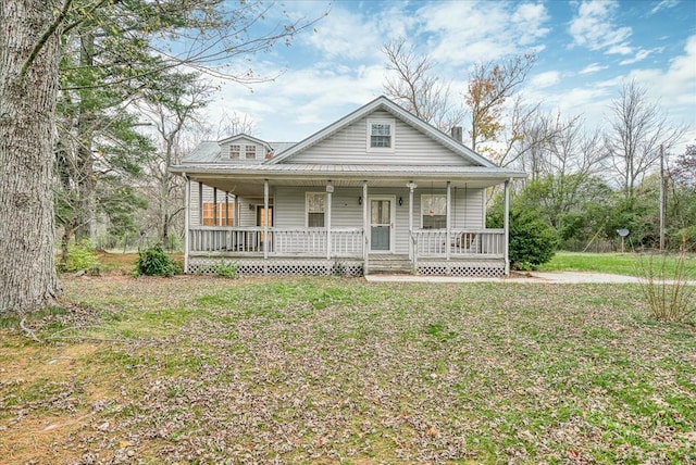 view of front of home featuring covered porch, metal roof, and a front lawn