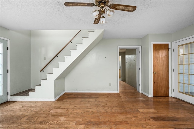 entrance foyer with baseboards, a ceiling fan, stairway, wood finished floors, and a textured ceiling