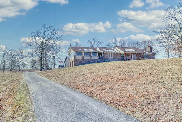 single story home featuring brick siding, a chimney, and a front lawn