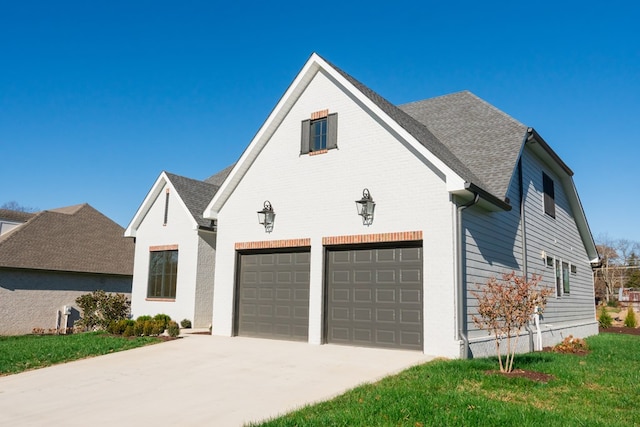 view of front facade featuring brick siding, a shingled roof, a front yard, a garage, and driveway