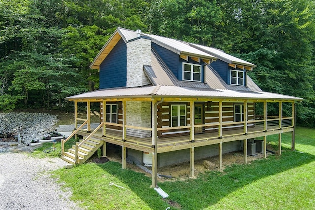 view of front of house with metal roof, central AC unit, covered porch, log siding, and a front yard