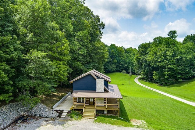 view of front of house featuring metal roof, stairs, a front lawn, and a porch