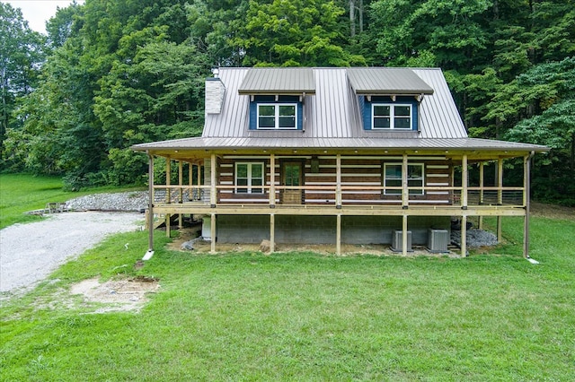 view of front of house featuring a front yard, metal roof, driveway, and a chimney