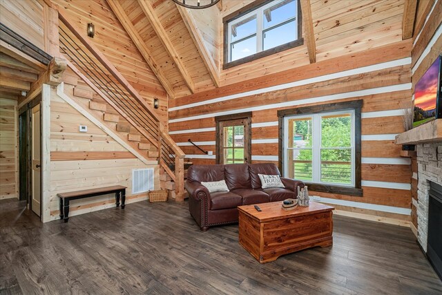 living room with wooden walls, visible vents, dark wood finished floors, and a stone fireplace