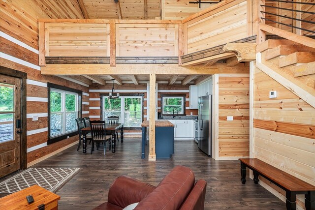 dining space with wood walls, a high ceiling, stairway, and dark wood finished floors