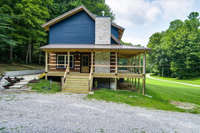 view of front of house featuring a front yard, covered porch, metal roof, and a chimney