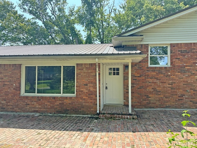 view of exterior entry with brick siding and metal roof