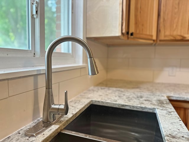 details featuring tasteful backsplash, light stone countertops, and a sink