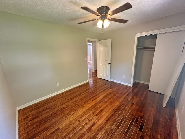 unfurnished bedroom featuring baseboards, dark wood-style flooring, a closet, and a textured ceiling