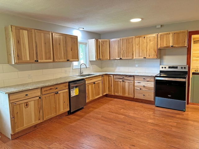 kitchen featuring backsplash, appliances with stainless steel finishes, light wood-type flooring, and a sink