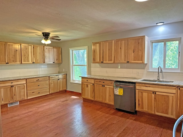 kitchen featuring visible vents, dishwasher, light wood-type flooring, decorative backsplash, and a sink