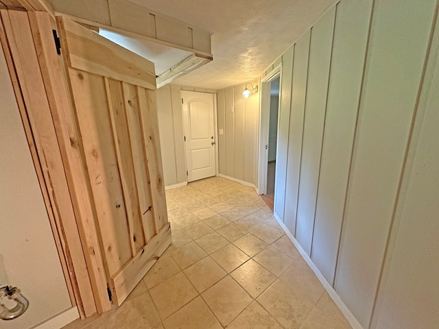 hallway featuring a decorative wall and light tile patterned flooring