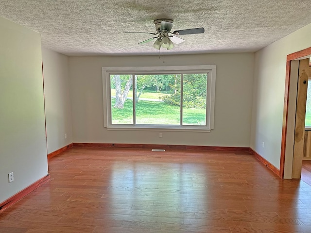 empty room with visible vents, baseboards, ceiling fan, wood finished floors, and a textured ceiling