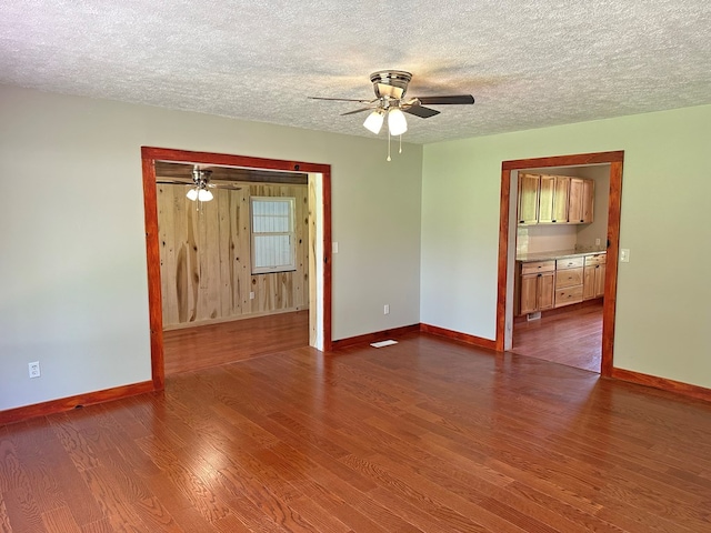 unfurnished room with baseboards, a textured ceiling, ceiling fan, and dark wood-style flooring