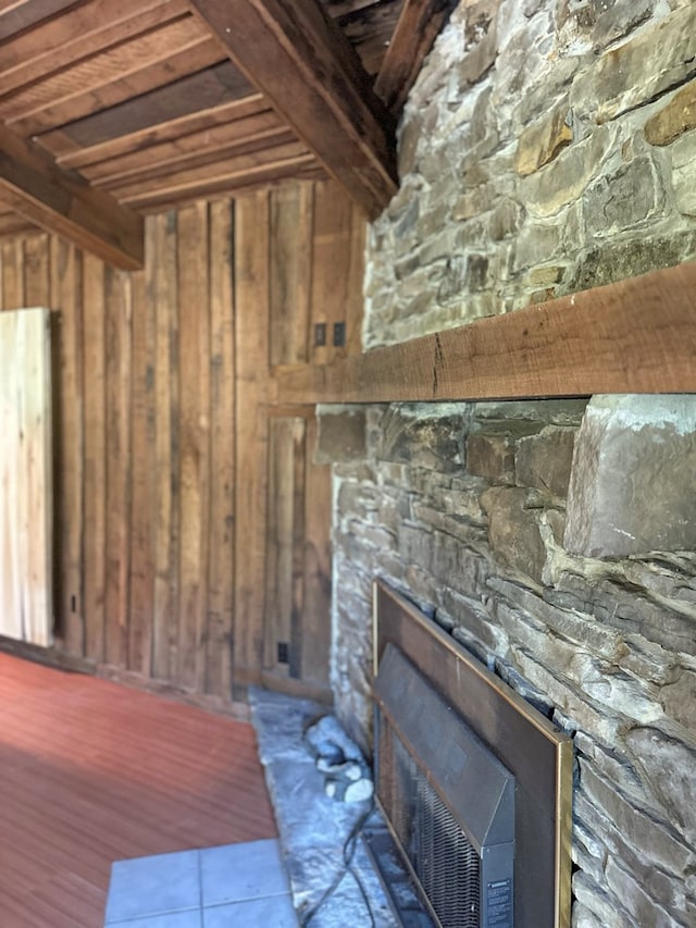 interior space with beam ceiling, wood walls, and a fireplace