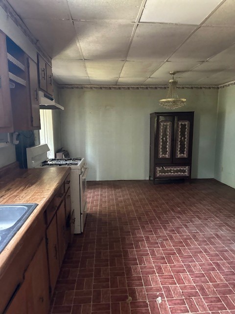 kitchen featuring under cabinet range hood, a sink, and gas range gas stove