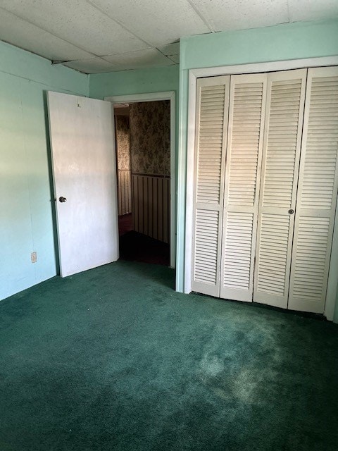 unfurnished bedroom with dark colored carpet and a closet