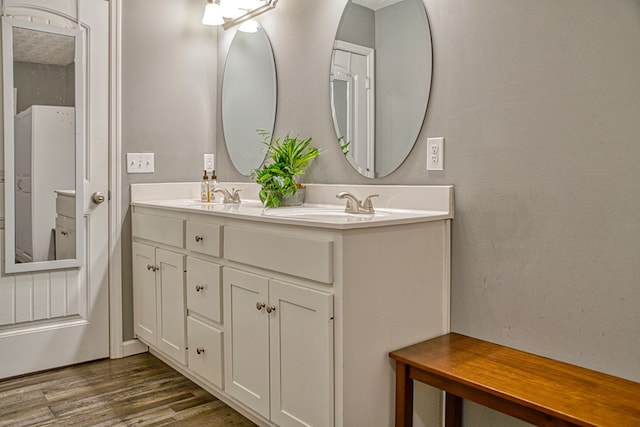 bathroom with double vanity, a sink, and wood finished floors