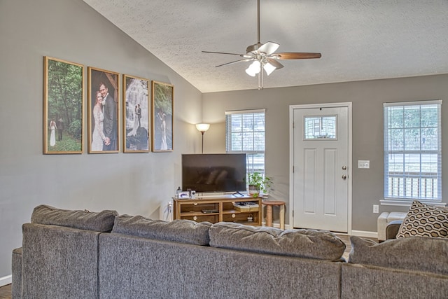 living area featuring lofted ceiling, ceiling fan, a textured ceiling, and baseboards