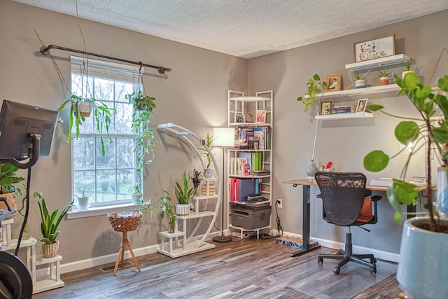 home office featuring a healthy amount of sunlight, a textured ceiling, baseboards, and wood finished floors