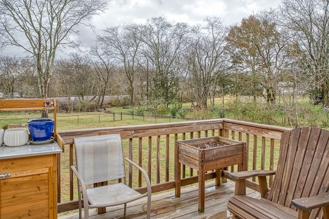 wooden deck featuring an outdoor fire pit, a lawn, and fence