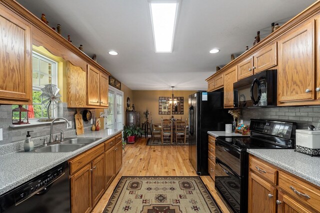 kitchen with a sink, light countertops, black appliances, brown cabinetry, and pendant lighting