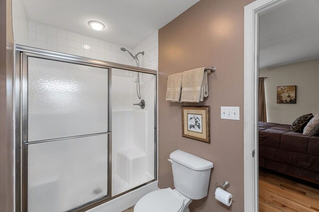 full bath featuring toilet, ensuite bath, wood finished floors, and a shower with shower door