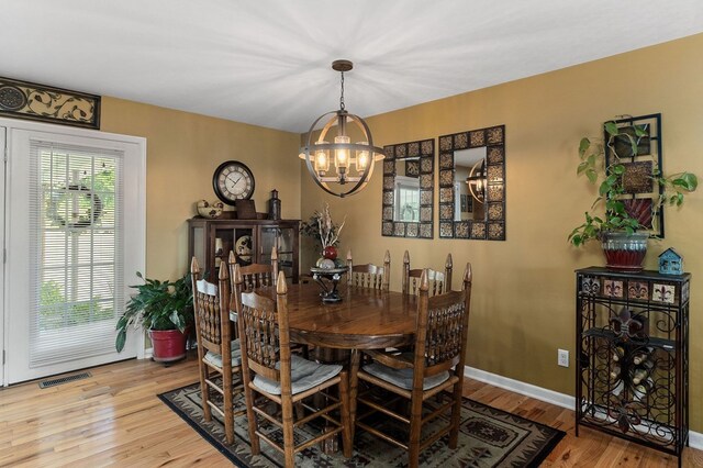 dining space with light wood finished floors, baseboards, visible vents, and an inviting chandelier