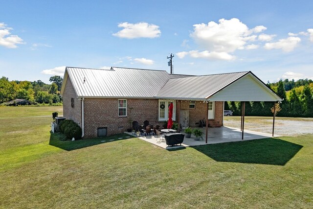 rear view of house with a patio area, brick siding, a yard, and metal roof