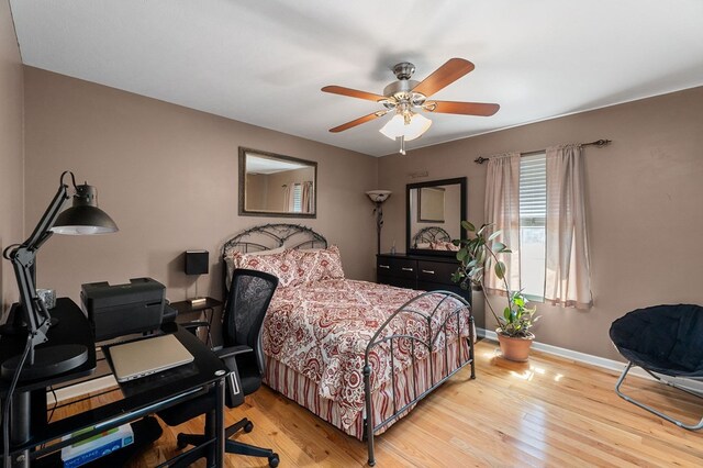 bedroom with light wood-type flooring, ceiling fan, and baseboards