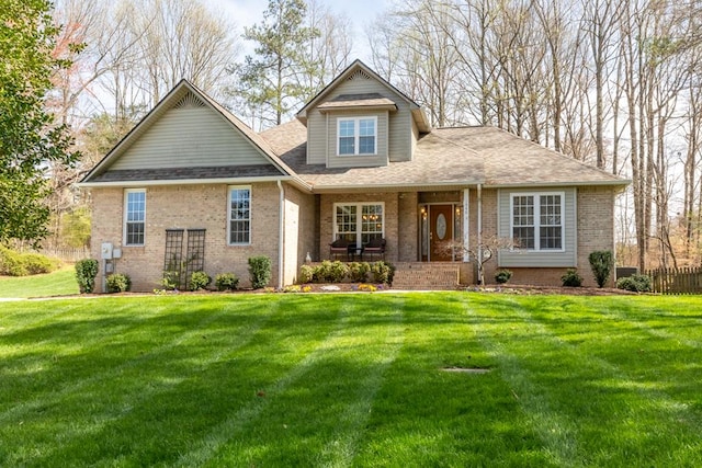 view of front of home with brick siding, a front lawn, and roof with shingles