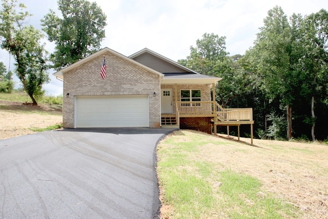 view of front of property with aphalt driveway, a porch, an attached garage, brick siding, and a front yard