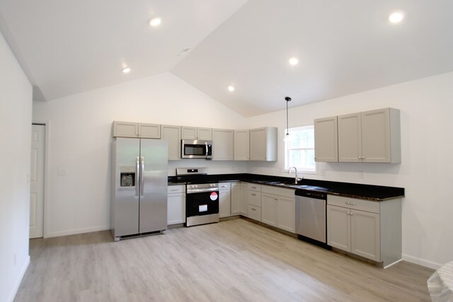 kitchen featuring dark countertops, light wood-style flooring, appliances with stainless steel finishes, pendant lighting, and a sink