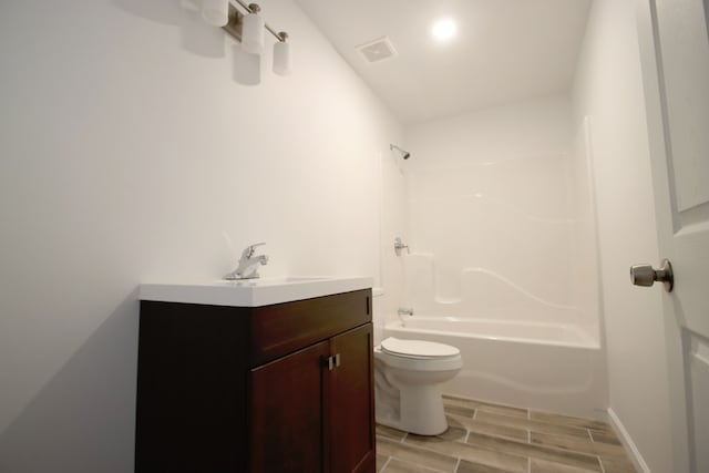 bathroom with toilet, wood finish floors, visible vents, vanity, and  shower combination