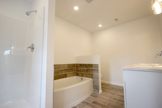 full bathroom featuring a garden tub, recessed lighting, wood finish floors, vanity, and baseboards