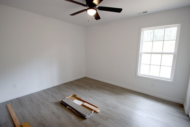 unfurnished room featuring ceiling fan, light wood-type flooring, visible vents, and baseboards