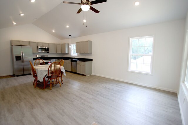 kitchen featuring gray cabinetry, a sink, appliances with stainless steel finishes, dark countertops, and pendant lighting