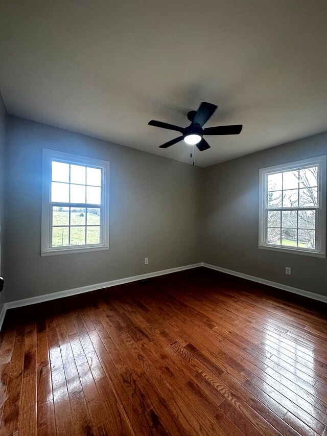 empty room featuring a ceiling fan, dark wood finished floors, and baseboards