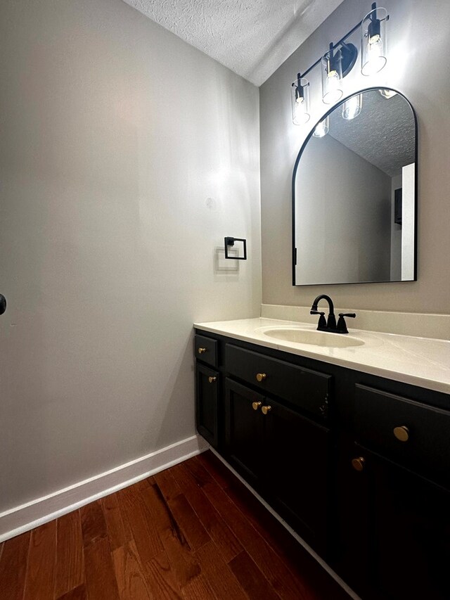 bathroom featuring a textured ceiling, wood finished floors, vanity, and baseboards