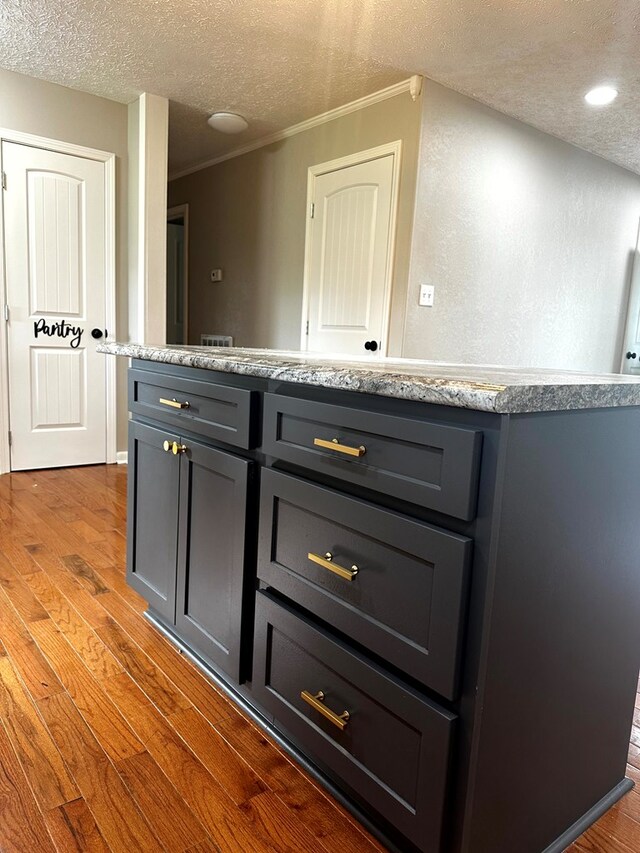 kitchen with ornamental molding, dark wood-style flooring, gray cabinets, a textured ceiling, and light countertops