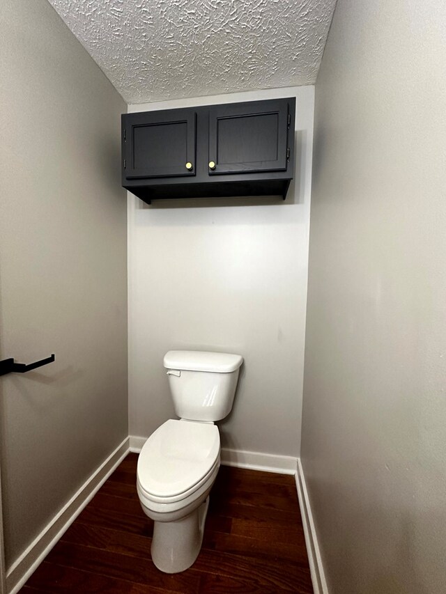 bathroom with toilet, a textured ceiling, baseboards, and wood finished floors